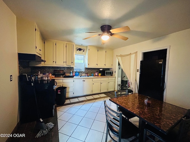 kitchen with tasteful backsplash, ceiling fan, white cabinets, light tile patterned floors, and black refrigerator