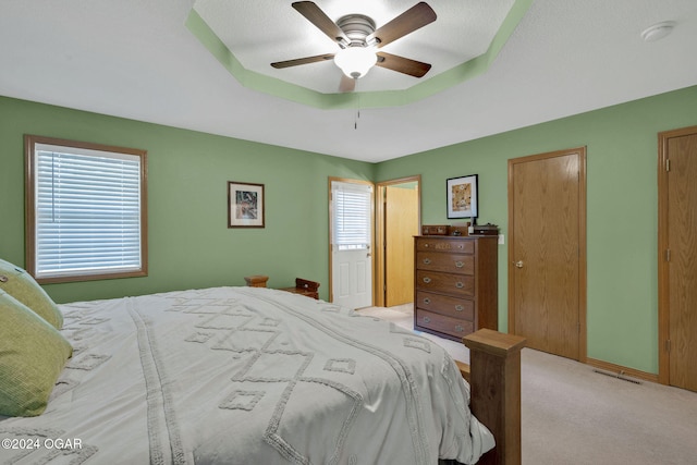 bedroom featuring light carpet, multiple windows, a textured ceiling, and ceiling fan