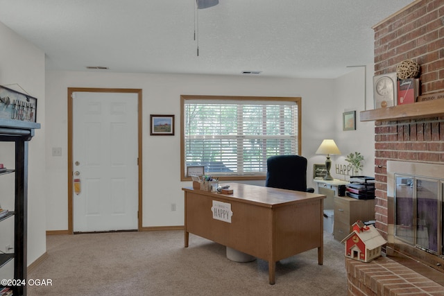 office area featuring light carpet, a textured ceiling, and a brick fireplace