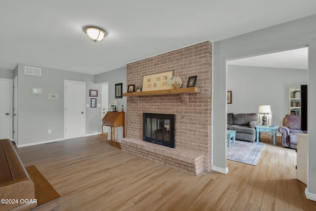 living room featuring hardwood / wood-style flooring and a brick fireplace