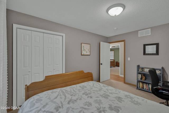 carpeted bedroom featuring a closet and a textured ceiling