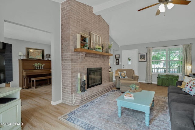 living room featuring ceiling fan, high vaulted ceiling, beamed ceiling, a fireplace, and light hardwood / wood-style floors