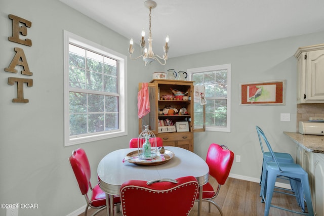 dining area with light hardwood / wood-style floors, an inviting chandelier, and a wealth of natural light