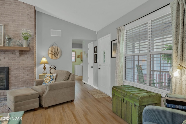 living room with hardwood / wood-style flooring, vaulted ceiling, and a fireplace