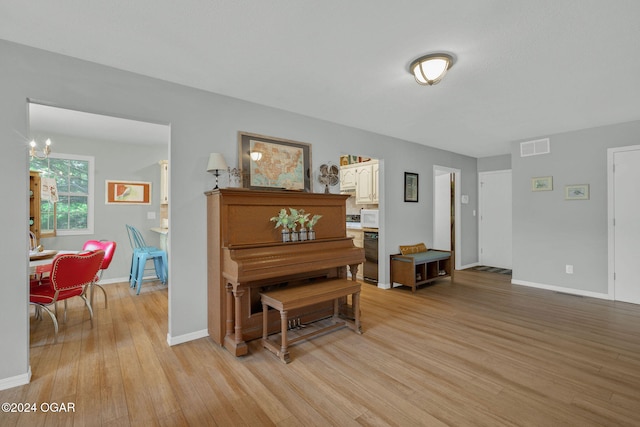 miscellaneous room with a chandelier and light wood-type flooring