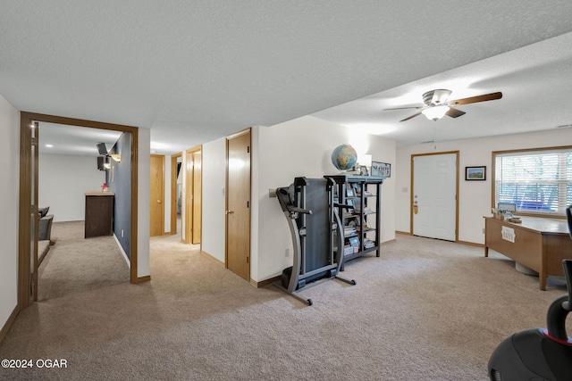 exercise room featuring ceiling fan, a textured ceiling, and light colored carpet