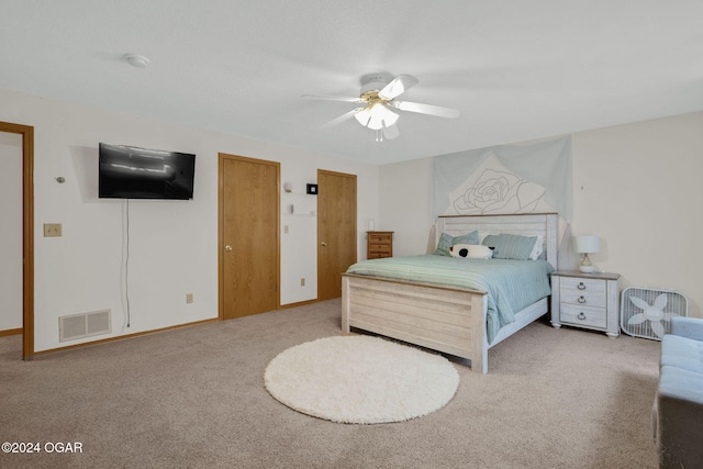 bedroom with ceiling fan, carpet, and two closets