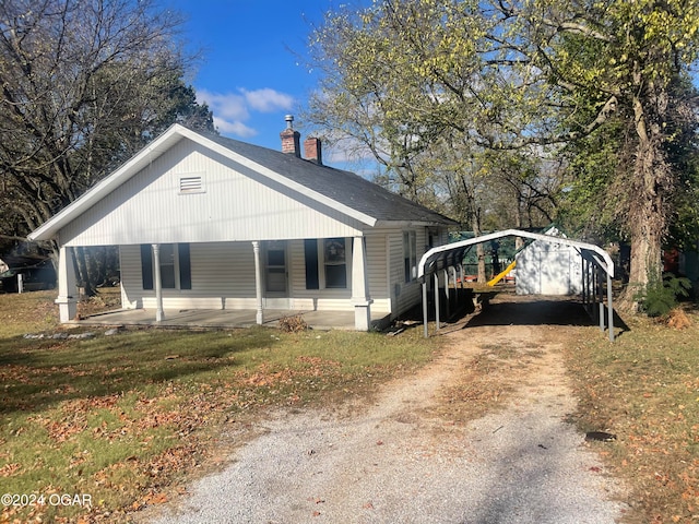 view of side of home featuring a lawn, a porch, and a carport