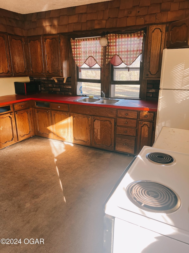 kitchen featuring white appliances, carpet floors, and sink