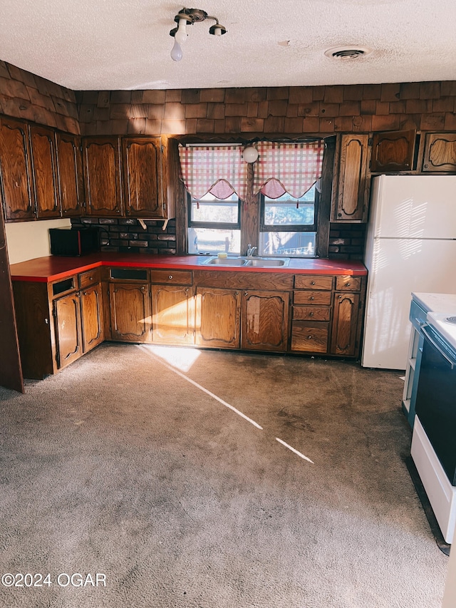 kitchen featuring sink, dark colored carpet, white refrigerator, a textured ceiling, and range