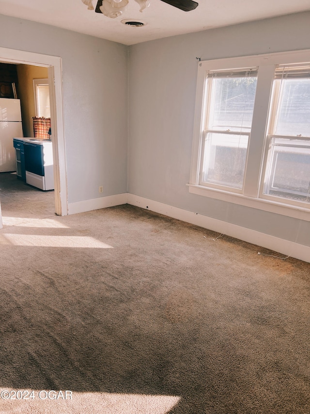 carpeted spare room featuring ceiling fan