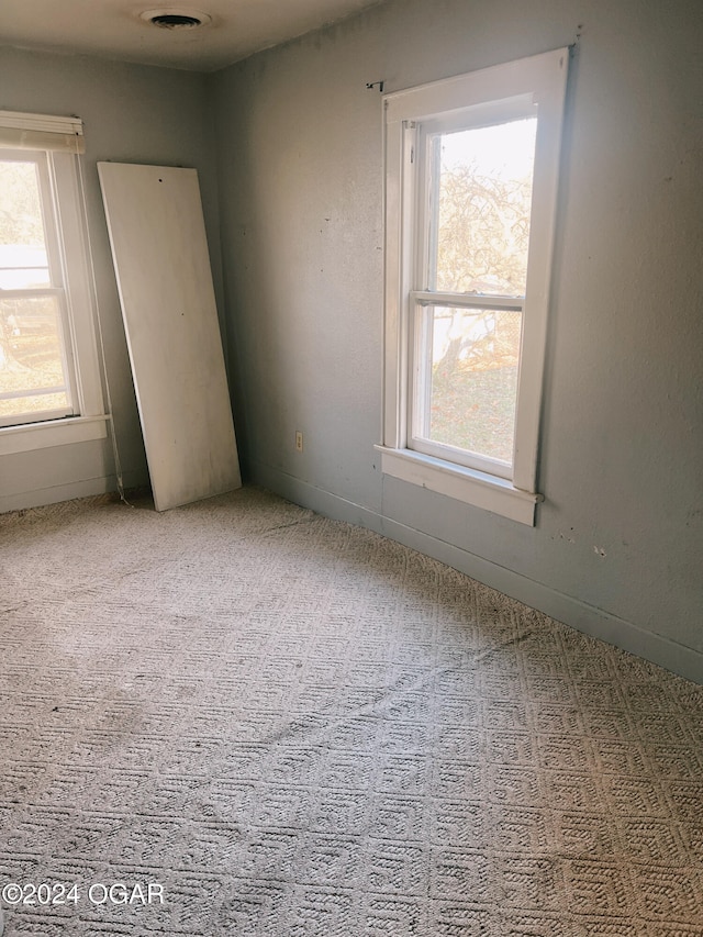 unfurnished room featuring light carpet and a wealth of natural light