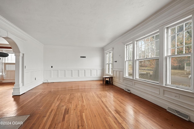 unfurnished room featuring ornate columns, crown molding, and light hardwood / wood-style flooring