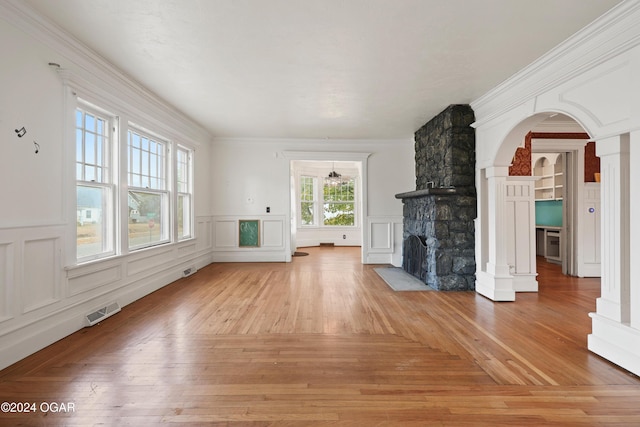 unfurnished living room with crown molding, a fireplace, light wood-type flooring, and plenty of natural light