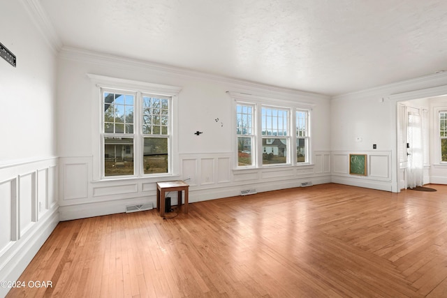 unfurnished living room with ornamental molding, hardwood / wood-style floors, a textured ceiling, and plenty of natural light