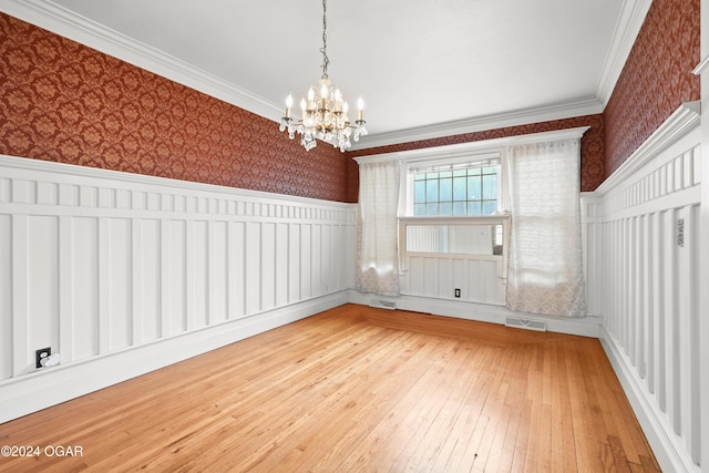 unfurnished room with a notable chandelier, wood-type flooring, and crown molding