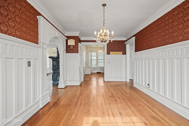 unfurnished dining area featuring ornamental molding, a chandelier, and light wood-type flooring