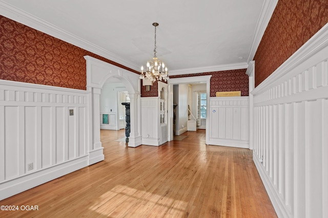 unfurnished dining area featuring crown molding, light hardwood / wood-style flooring, and an inviting chandelier