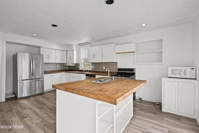 kitchen featuring butcher block counters, stainless steel appliances, sink, white cabinetry, and light hardwood / wood-style floors