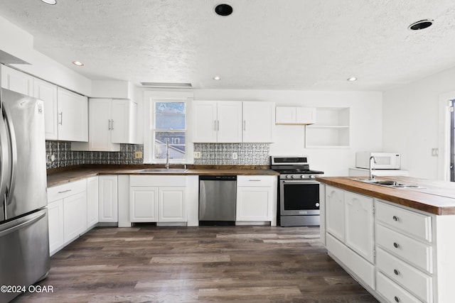 kitchen featuring white cabinets, stainless steel appliances, and wood counters