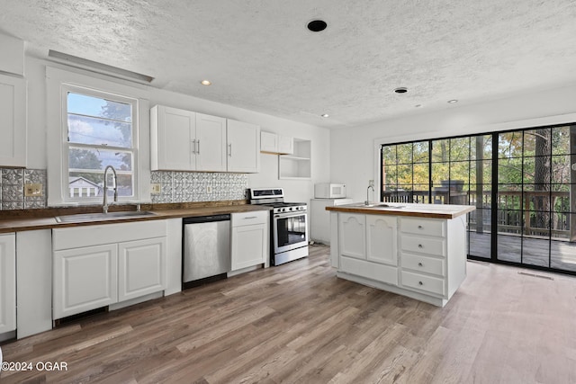 kitchen with appliances with stainless steel finishes, white cabinetry, sink, and a wealth of natural light