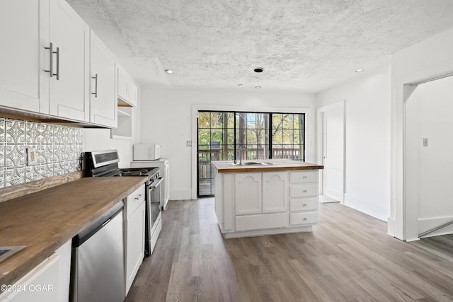 kitchen with light wood-type flooring, butcher block counters, stainless steel appliances, and white cabinetry