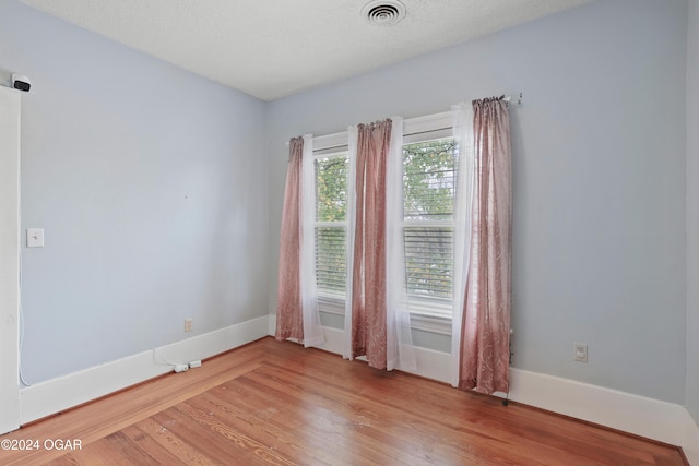 unfurnished room featuring wood-type flooring and a textured ceiling