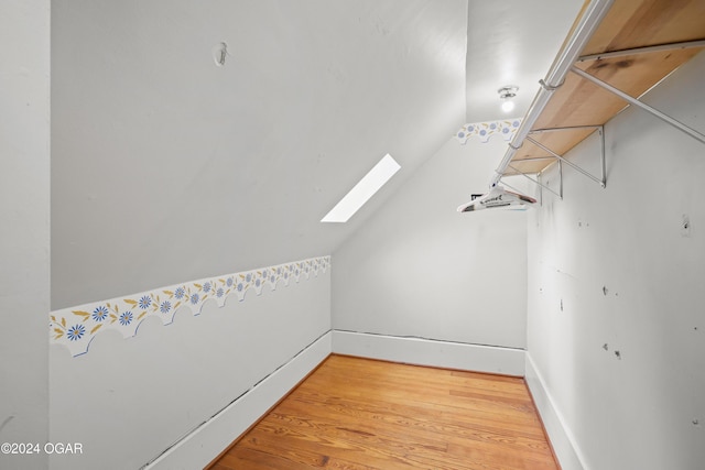 additional living space with vaulted ceiling with skylight and hardwood / wood-style flooring