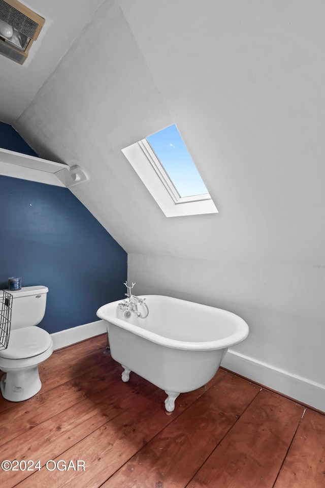 bathroom featuring toilet, lofted ceiling, a washtub, and hardwood / wood-style floors