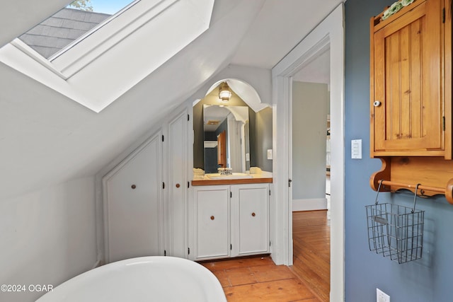 bathroom with vanity, lofted ceiling with skylight, and hardwood / wood-style floors