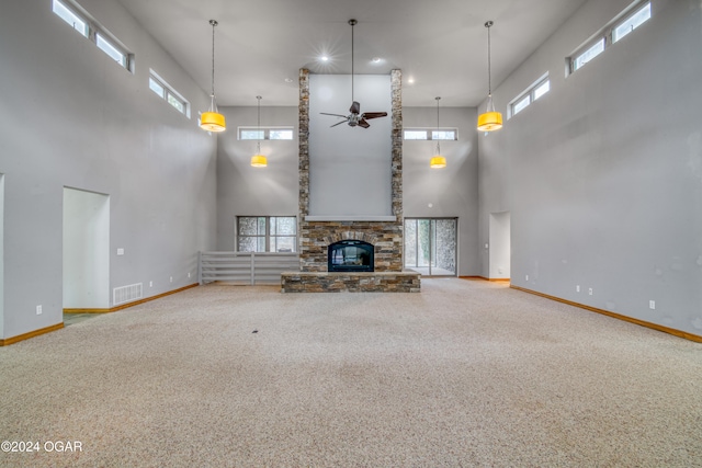 unfurnished living room featuring plenty of natural light, ceiling fan, carpet floors, and a towering ceiling