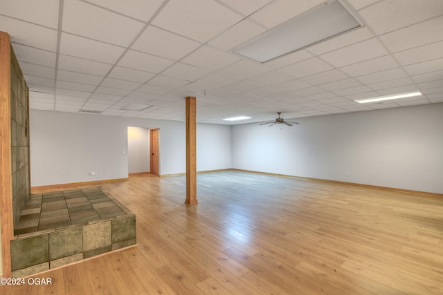 basement with a paneled ceiling, ceiling fan, and light hardwood / wood-style floors