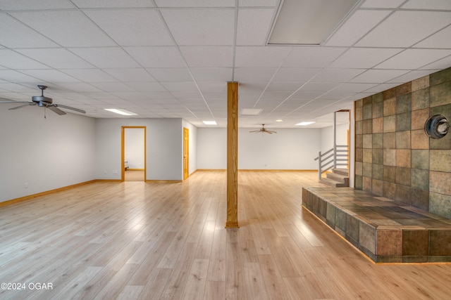 basement with ceiling fan, a paneled ceiling, and light wood-type flooring