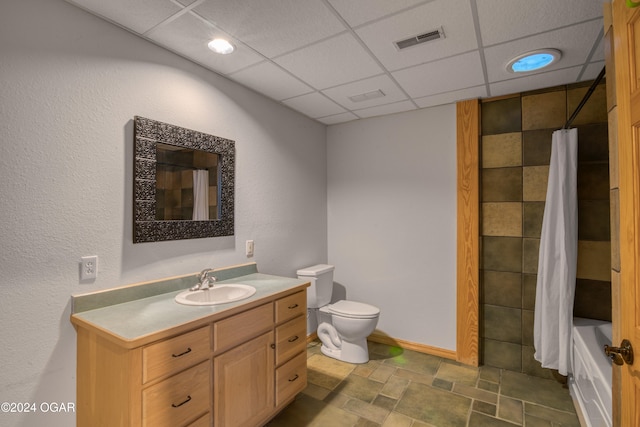 full bathroom featuring shower / bath combo, vanity, toilet, and a drop ceiling