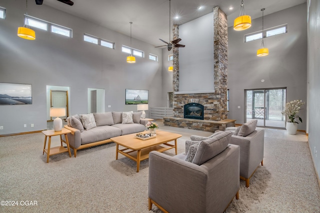 carpeted living room featuring a fireplace, ceiling fan, and a high ceiling