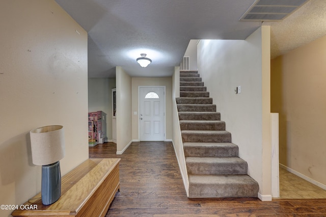 foyer entrance with a textured ceiling and dark hardwood / wood-style flooring