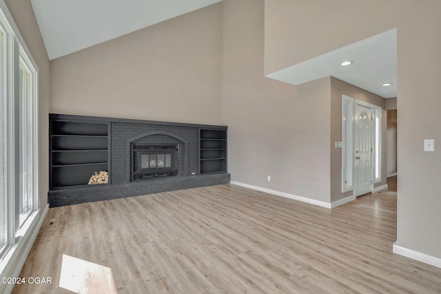 unfurnished living room with light hardwood / wood-style flooring, lofted ceiling, and a fireplace