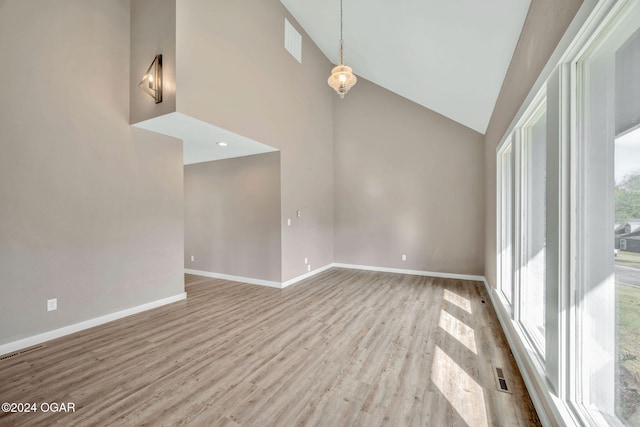 empty room with light hardwood / wood-style flooring and high vaulted ceiling