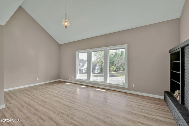 unfurnished living room with light hardwood / wood-style flooring, high vaulted ceiling, and a fireplace