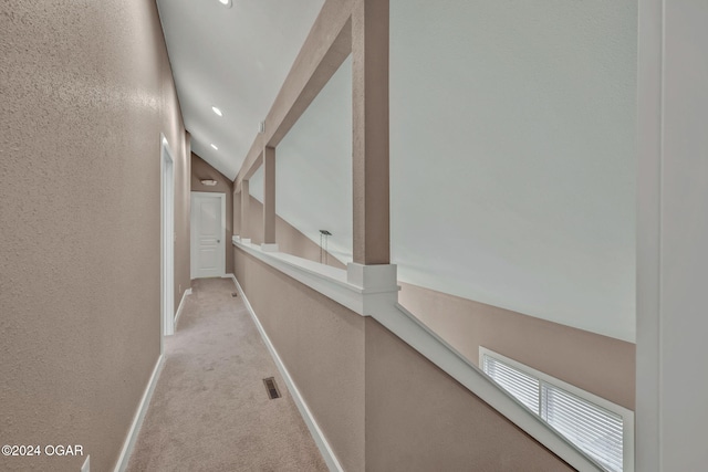 corridor with vaulted ceiling and light colored carpet