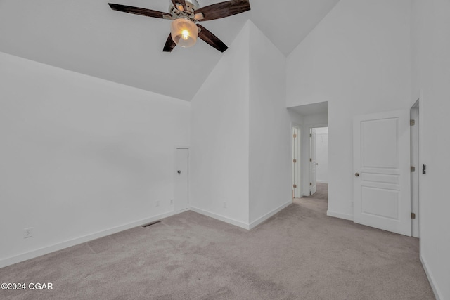 spare room with ceiling fan, high vaulted ceiling, and light colored carpet