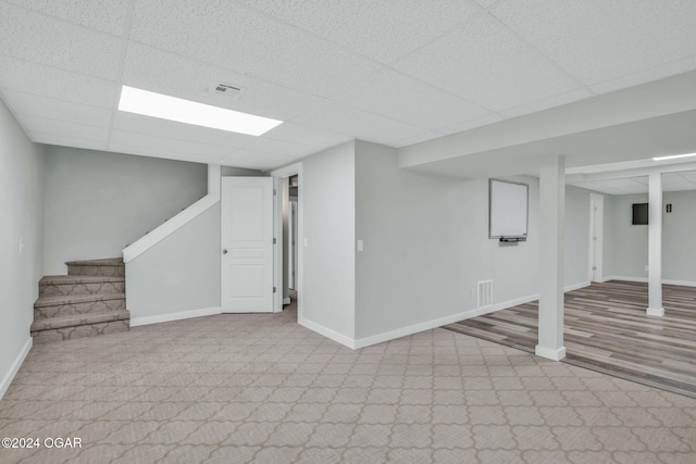 basement with a paneled ceiling and light hardwood / wood-style floors