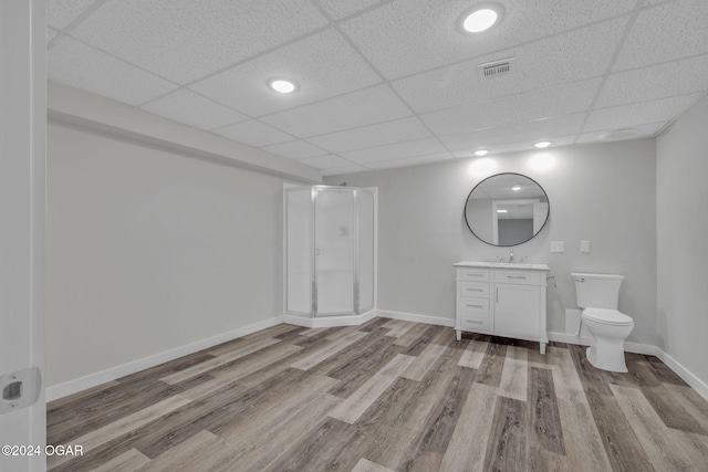 bathroom featuring a shower with door, wood-type flooring, toilet, vanity, and a drop ceiling