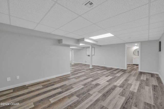 basement featuring a drop ceiling and light hardwood / wood-style flooring