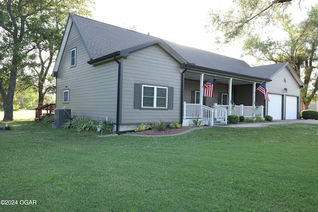 view of front of home featuring covered porch, a garage, a front lawn, and central AC unit