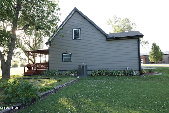 view of home's exterior featuring a deck, a lawn, and central AC unit