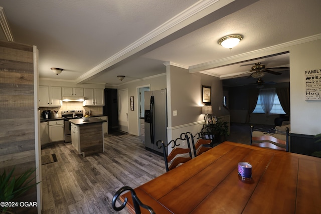 dining space featuring dark wood-type flooring, crown molding, a textured ceiling, and ceiling fan