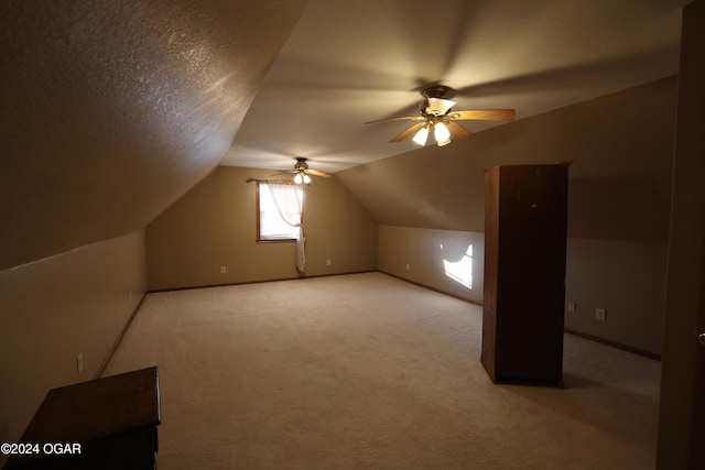 bonus room featuring lofted ceiling, a textured ceiling, light colored carpet, and ceiling fan