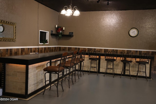 bar with an inviting chandelier and concrete flooring