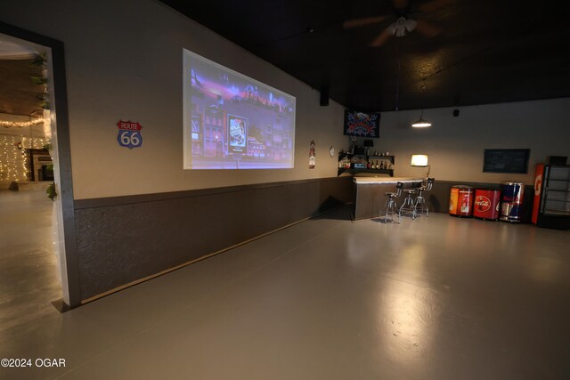 cinema room featuring concrete flooring and ceiling fan